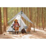 Young woman tourist sitting near the tent and reading a book. pe