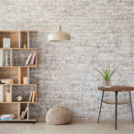 Interior of modern room with bookcase, pouf and lamp