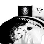 Lamp on wooden table next to a blue and white bed in bedroom int